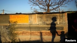 The shadows of a mother and child are cast on a shack in Marikana's Nkaneng township in Rustenburg, 100 km (62 miles) northwest of Johannesburg, August 15, 2013.