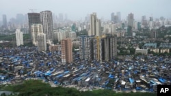 Daerah kumuh dan gedung-gedung tinggi terlihat di latar belakang di Mumbai, India, Selasa, 23 Juli 2024. (Rajanish Kakade/AP)