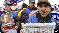 Protesters hold manipulated pictures of government leaders, Bucharest, Jan. 24, 2012.