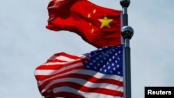 FILE - Chinese and U.S. flags flutter near The Bund before U.S. trade delegation meets its Chinese counterparts for talks in Shanghai, China, July 30, 2019. 