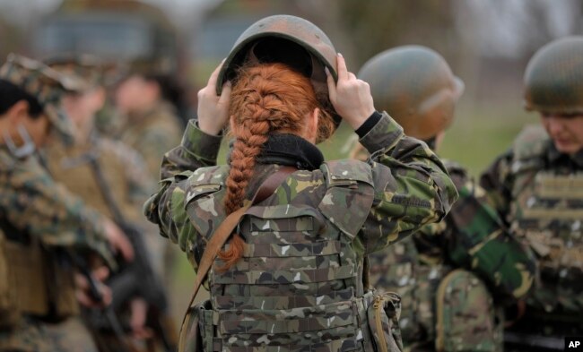 رومانیہ کی خواتین فوجی اہلکار امریکہ کی خواتین اہلکاروں کے ساتھ ٹریننگ کرتے ہوئے چٹیا بندھے ہوئے ہیں۔ (فائل فوٹو)