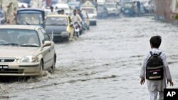 A boy walks near vehicles through a flooded street after heavy rains in Peshawar August 25, 2011