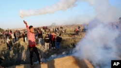 A Palestinian protester throws back a teargas canister that was fired by Israeli soldiers, during clashes on the Israeli border following a protest against U.S. President Donald Trump's decision to recognize Jerusalem as the capital of Israel, east of Gaz