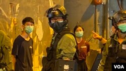 兩名高舉抗議警方標語的年輕人被警員截查。(美國之音湯惠芸)