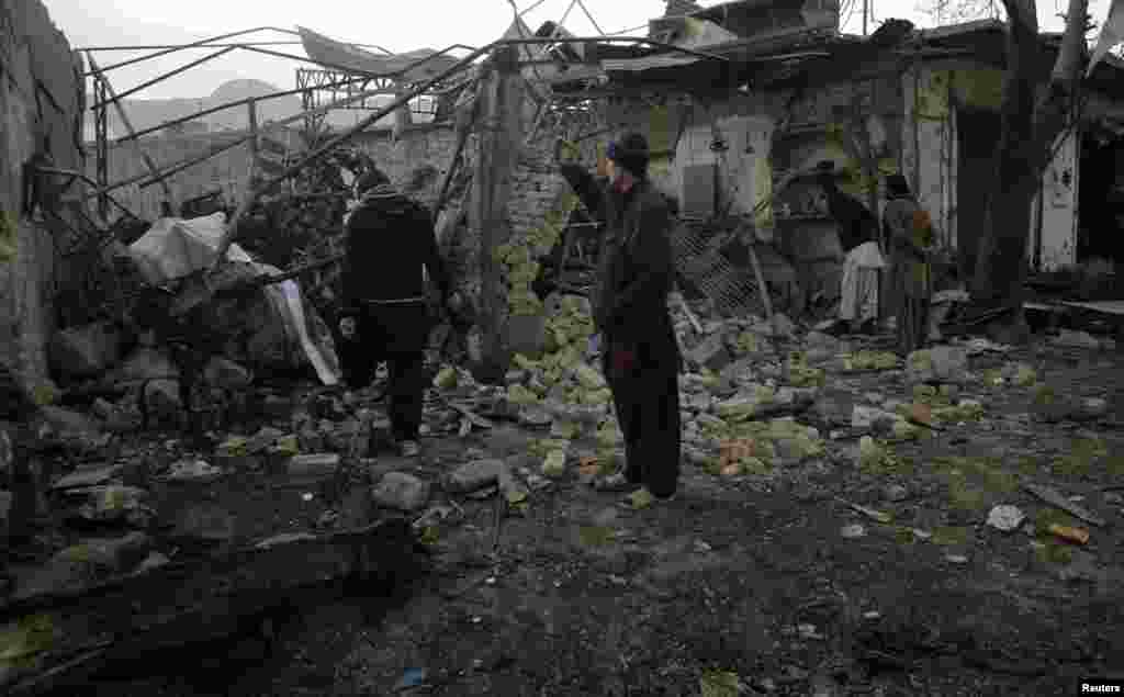 A man takes a photograph with his mobile phone of a house that was damaged by a bomb blast in Quetta, Pakistan, January 11, 2013. 
