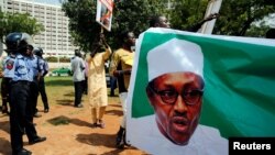 Supporters of President Muhammadu Buhari rally in support of his administration as police officers look on, at the Unity fountain in Abuja, Nigeria, Aug. 11, 2017. 