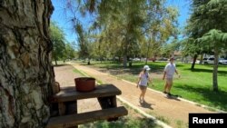 Personas usando máscaras caminan en un parque en el área de Valley Village, en Los Ángeles, California. 7 de agosto de 2020.