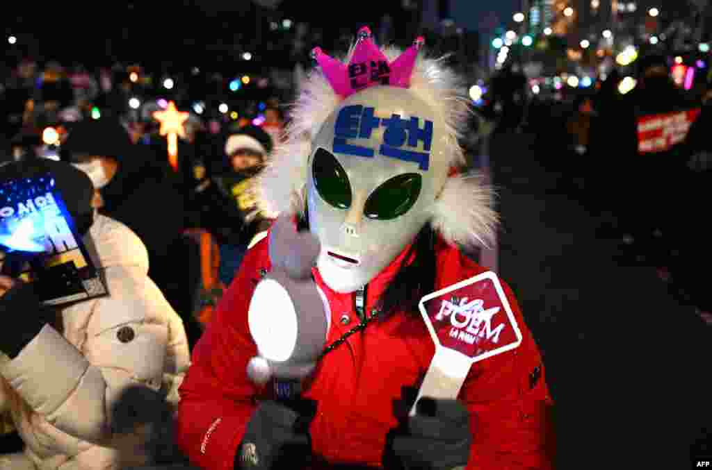 A man wearing a mask with the word &quot;Impeachment&quot; written on it waves light sticks as he takes part in a protest calling for the ouster of South Korea President Yoon Suk Yeol, near the National Assembly in Seoul.