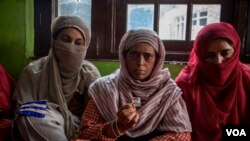 Mother and two relatives of Kashmiri student Arshid Yusuf who was arrested in Uttar Pradesh for sharing congratulatory WhatsApp messages in support of Pakistani cricket team.The mother is showing a photo of the arrested son. (VOA/Faisal Bashir)