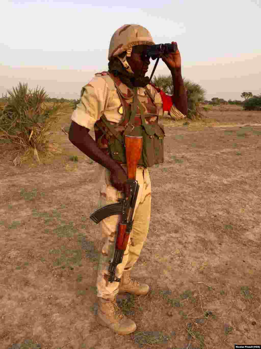 Un soldat nigérien observe la rive nigériane de la Komadogou, cette rivière qui sépare les deux pays, le 29 février 2016. (VOA/Nicolas Pinault)