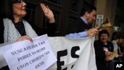 Para pegawai pemerintahan di Pamplona, Spanyol, berunjuk rasa menentang keterpurukan ekonomi negara itu. Kertas yang dibawa protester ini berbunyi "Tidak ada negara semiskin ini yang telah membuat sejumpah pencurinya begitu kaya".