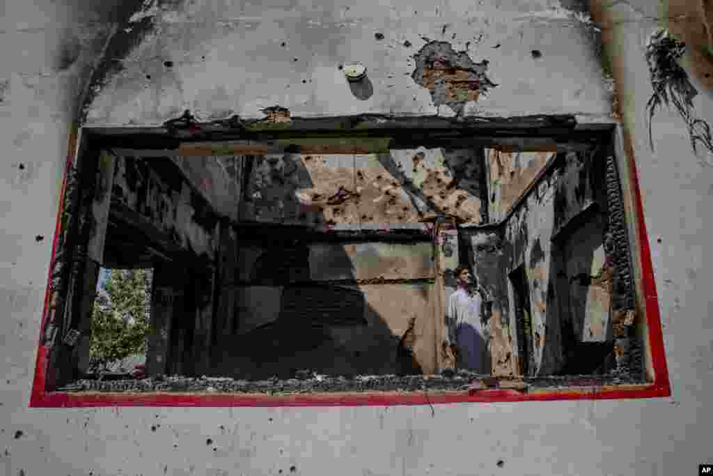 A Kashmiri villager inspects the house damaged during a gun battle between Indian soldiers and suspected militants in Kakpora village about 30 kilometers south of Srinagar, Indian controlled Kashmir.