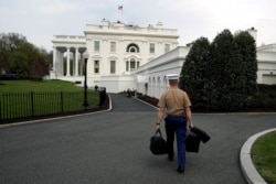 Un militar carga los maletines con los códigos nucleares tras el regreso a la Casa Blanca del presidente Donald Trump después de un viaje a la Florida el 22 de abril de 2018.