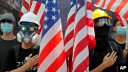 Pro-democracy university students hold U.S. flags and sing the Star-Spangled Banner at the campus of the University of Hong Kong, Friday, Sept. 20, 2019.