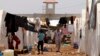 FILE - Syrian refugees walk under clothing lines at the Bab Al-Salam refugee camp in Azaz, near the Syrian-Turkish border, June 9, 2013. 