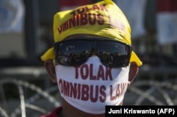 Seorang aktivis memprotes omnibus law pemerintah tentang penciptaan lapangan kerja, yang mereka yakini akan mencabut hak pekerja, Surabaya, 25 Agustus 2020. (Foto: AFP/Juni Kriswanto)