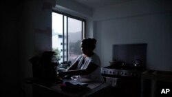 Orelis Lehmann gets set to make coffee in her darkened apartment in Caracas, Venezuela, July 23, 2019. In neighborhoods like hers, darkness from a power outage lingered even as other parts of Caracas began springing back to life.