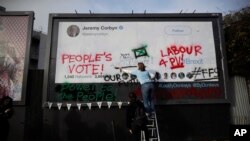 Members of Britain's Labor Party write on a billboard why they want party leader Jeremy Corbyn to back a second referendum on Britain's European Union membership, during a publicity stunt in Islington North, Corbyn's north London constituency, Feb. 12, 2019.