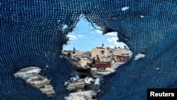 Palestinians, seen through a torn tent, ride a motorized vehicle past the rubble, amid the Israel-Hamas conflict, in Khan Younis, in the southern Gaza Strip, Sept. 16, 2024. 