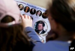 Michelle, right, and Matilda Chipperfield of England look at photos of U.S. presidents while visiting Dealey Plaza in downtown Dallas, Oct. 25, 2017.