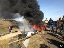 Dakota Access oil pipeline protesters burn debris as officers close in to force them from a camp on private land in the path of pipeline construction, Oct. 27, 2016 near Cannon Ball, N.D.