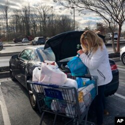 FILE - A shopper loads groceries into her car, Dec. 17, 2020, in Dover, Del. Starting Jan. 1, 2021, grocery stores and many other retailers in Delaware were prohibited from providing thin plastic bags to customers at checkout counters.