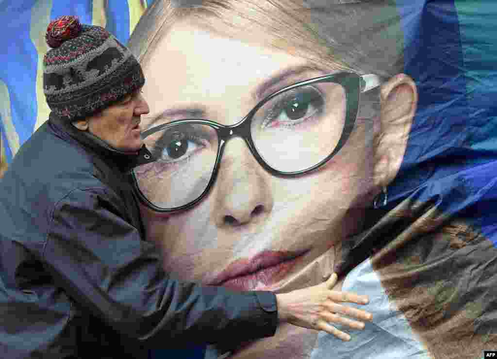 A supporter tries to stabilize a campaign booth of former Ukrainian Prime Minister and presidential candidate Yulia Tymoshenko during heavy wind in central Kiyev, ahead of Ukraine's presidential elections on March 31.