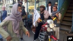 Un combattant taliban est assis sur sa moto ornée d'un drapeau taliban dans une rue à Kunduz, en Afghanistan (AP - 29 sept 2015)