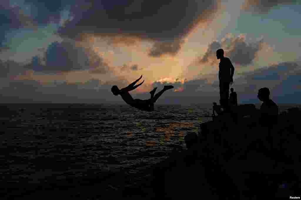 A Palestinian youth jumps into the water of the Mediterranean Sea on a hot day, at the seaport of Gaza City, June 28, 2019. 