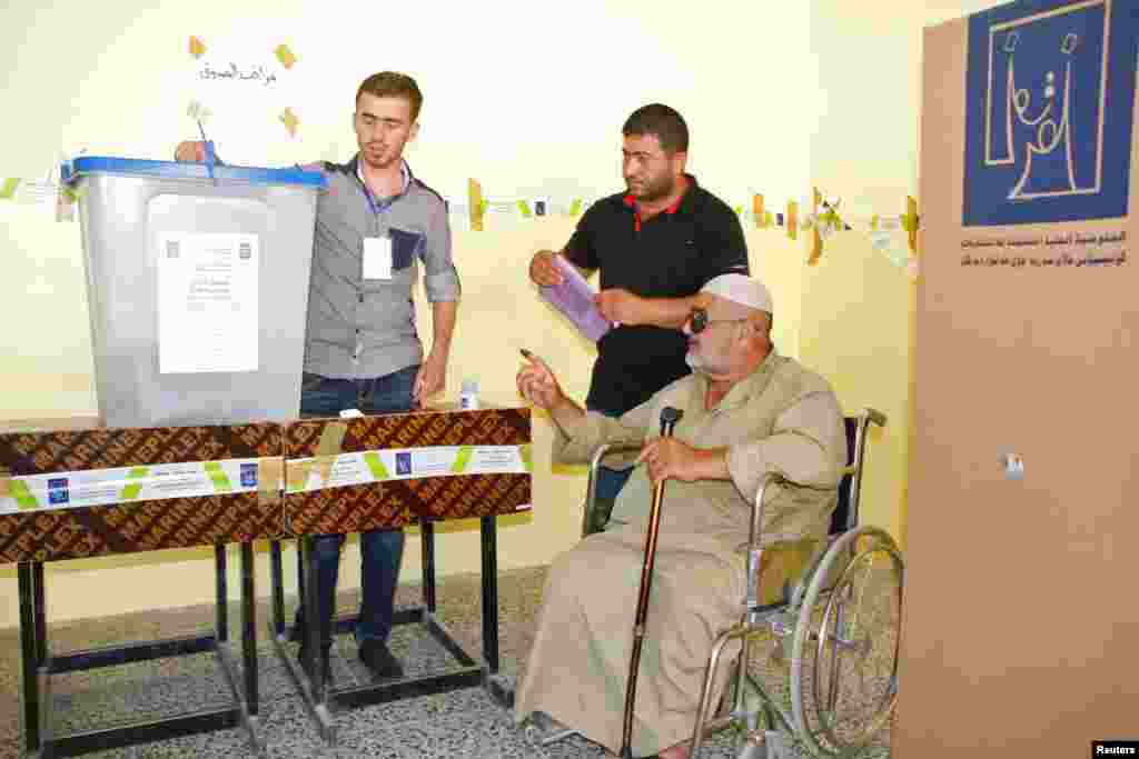 An elderly Iraqi man in a wheelchair receives help as he votes during Iraq&#39;s provincial elections at a polling station in Mosul, 390 km north of Baghdad, June 20, 2013.&nbsp;