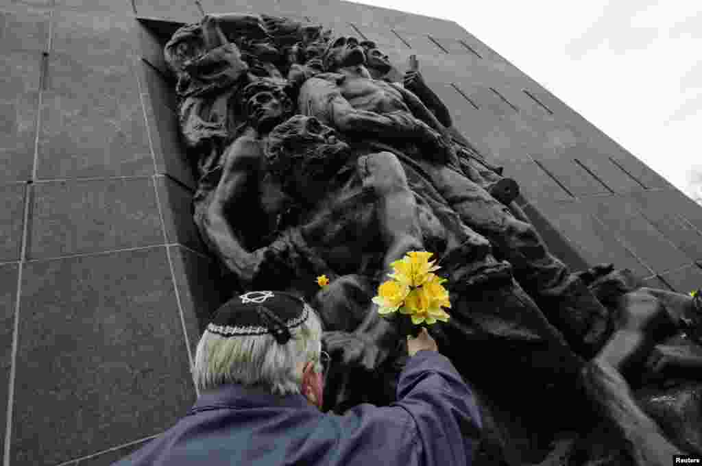 A man places a bunch of flowers at the Monument to the Ghetto after a ceremony commemorating the 70th anniversary of the Warsaw Ghetto Uprising in Warsaw, Poland. 