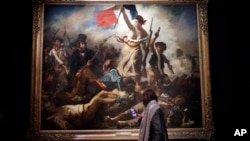 A woman looks at "La liberte guidant le peuple" ("Liberty Leading the People") by Eugene Delacroix at the Louvre, in Paris, March 27, 2018. The Louvre is presenting a retrospective of Delacroix's work.