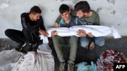 Twenty-year-old Ali Assaf, center, reportedly the only person in his family to survive an overnight Israeli airstrike in the Jabalia refugee camp in the northern Gaza Strip, is comforted as he mourns near the bodies of his relatives, Oct. 12, 2024. 