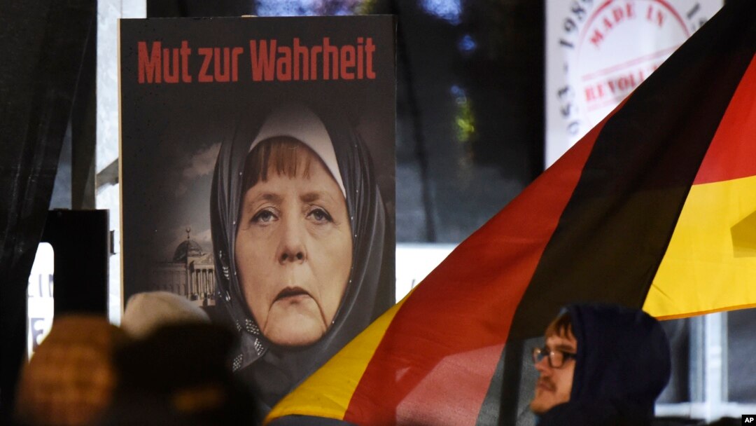 ARSIP – Sebuah poster dengan bunyi “Keberanian untuk Berbicara Jujur” menggambarkan Kanselir Jerman, Angela Merkel, mengenakan hijab di depan gedung Reichstag dengan bulan sabit di atasnya dalam sebuah demonstrain gerakan anti Islamisasi, Legida, gerakan turunan Pegida, di Leipzing, Jeman, 30 Januari 2015 (foto: AP Photo/Jens Meyer)