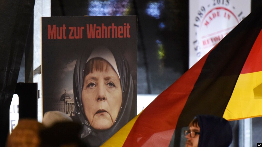 FILE -A poster with the writing "Courage to speak the truth" depicts German Chancellor Angela Merkel wearing a veil during a demonstration of the Legida anti-Islamization movement, an offshoot of Pegida, in Leipzig, Jan. 30, 2015. 