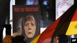 FILE -A poster with the writing "Courage to speak the truth" depicts German Chancellor Angela Merkel wearing a veil during a demonstration of the Legida anti-Islamization movement, an offshoot of Pegida, in Leipzig, Jan. 30, 2015. 