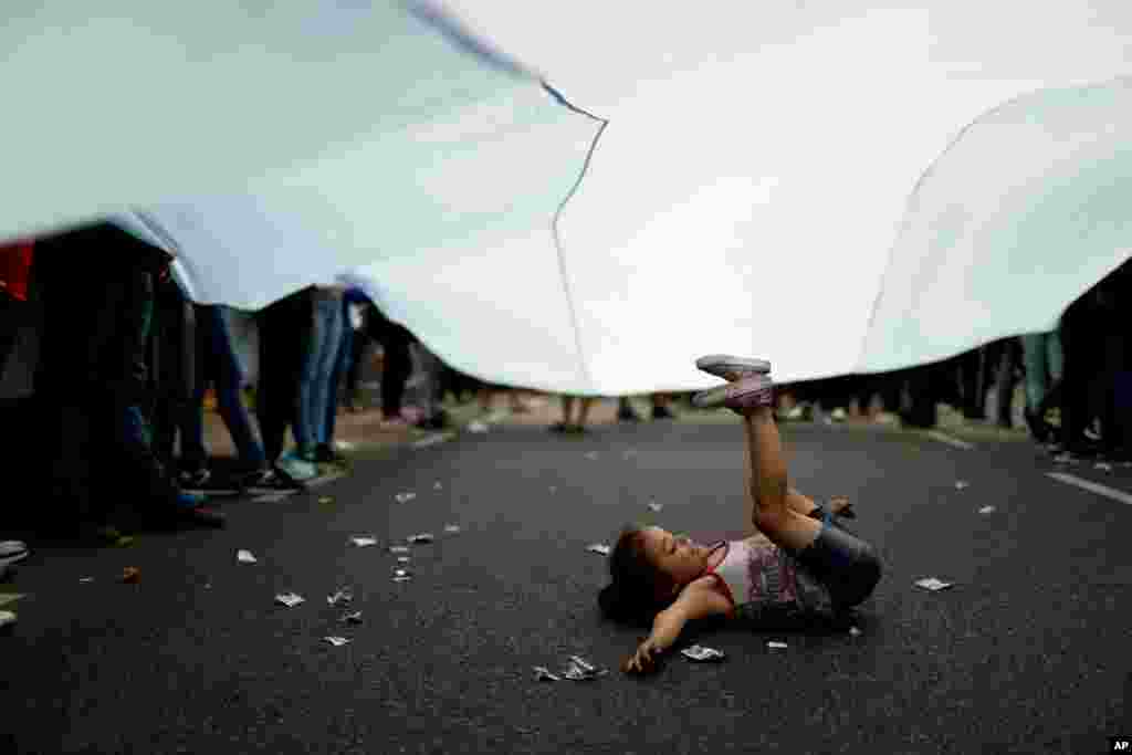 A girl plays beneath an Argentine flag as demonstrators protest against the increase in public service fees, in Buenos Aires, Argentina, Jan. 10, 2019.