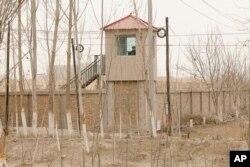 FILE - A security guard watches from a watchtower around a detention facility in Yarkent County in northwestern China's Xinjiang Uyghur Autonomous Region, March 21, 2021.