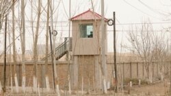 FILE - A security person watches from a guard tower around a detention facility in Yarkent County in northwestern China's Xinjiang Uyghur Autonomous Region, March 21, 2021.