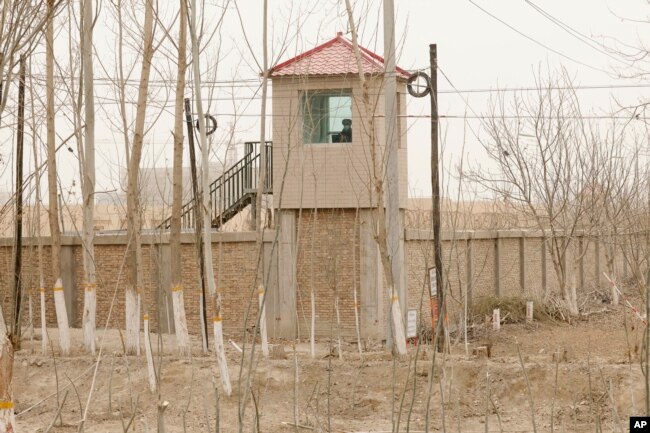 FILE - A security person watches from a guard tower around a detention facility in Yarkent County in northwestern China's Xinjiang Uyghur Autonomous Region, March 21, 2021.