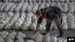 Seorang pekerja menyortir kantong tepung saat pendistribusian bantuan kemanusiaan di Kota Gaza pada 17 Maret 2024, di tengah pertempuran yang sedang berlangsung antara Israel dan kelompok militan Hamas. (Foto: AFP)