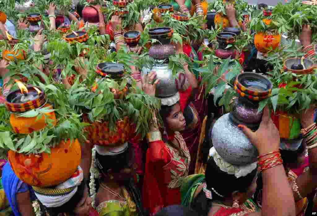 Women carry pots filled with cooked rice decorated with turmeric and neem leaves on their heads during the &#39;Bonalu&#39; festival in Hyderabad, India. Bonalu is a month-long Hindu folk festival of the Telangana region dedicated to the Hindu goddess Kali.