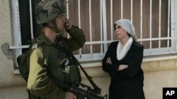 A Palestinian woman stands next to an Israeli soldier during a protest against the expansion of a Jewish settlement near the West Bank village of Nabi Saleh, Friday, Oct. 22, 2010.