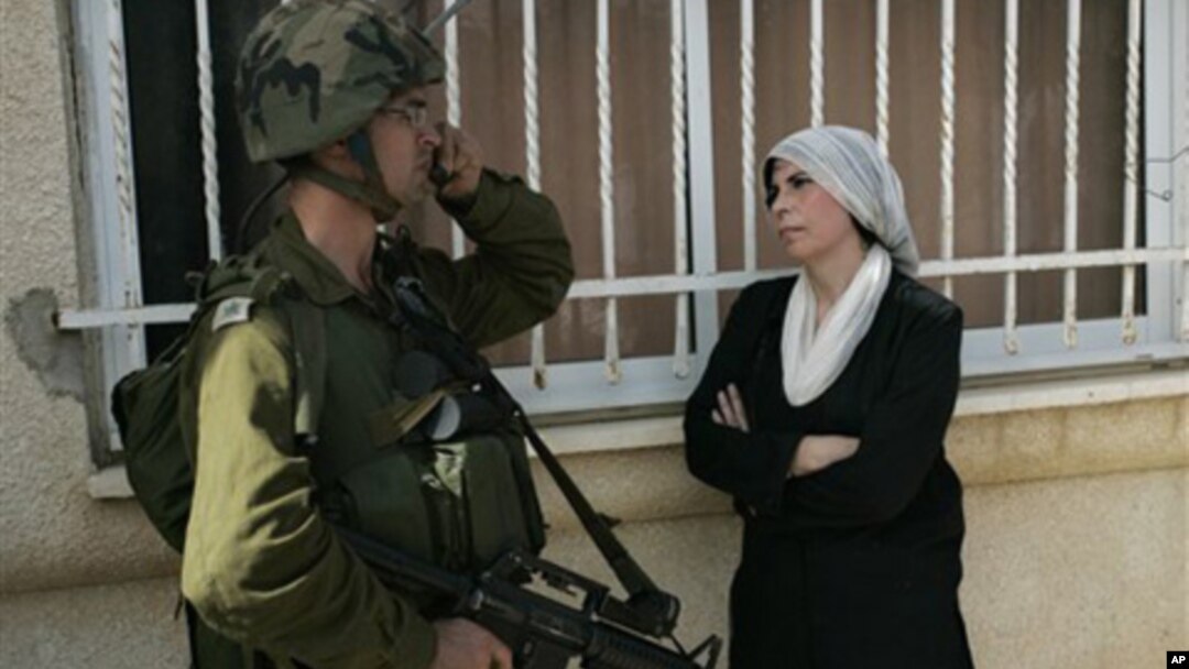 A Palestinian woman stands next to an Israeli soldier during a protest against the expansion of a Jewish settlement near the West Bank village of Nabi Saleh, Friday, Oct. 22, 2010.