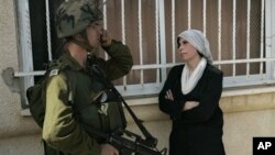 A Palestinian woman stands next to an Israeli soldier during a protest against the expansion of a Jewish settlement near the West Bank village of Nabi Saleh, Friday, Oct. 22, 2010.