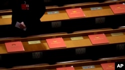 FILE - A delegate walks past copies of draft resolutions placed on delegates' desks of the annual National People's Congress in Beijing's Great Hall of the People, March 16, 2016. A revised controversial law that seeks to harshly regulate foreign NGOs in China is under review by the country's lawmakers.