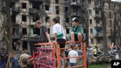 Los niños miran la escena del último ataque con cohetes rusos que dañó un edificio de apartamentos de varios pisos en Kryvyi Rih, Ucrania, el 13 de junio de 2023.