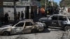 FILE - Residents walk past cars set on fire by armed gangs in the Poste Marchand neighborhood of Port-au-Prince, Haiti, Dec. 10, 2024.