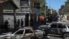 Residents walk past cars set on fire by armed gangs in the Poste Marchand neighborhood of Port-au-Prince, Haiti, Dec. 10, 2024. 