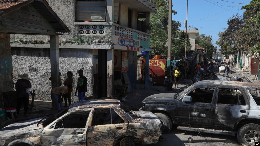 Residents walk past cars set on fire by armed gangs in the Poste Marchand neighborhood of Port-au-Prince, Haiti, Dec. 10, 2024. 